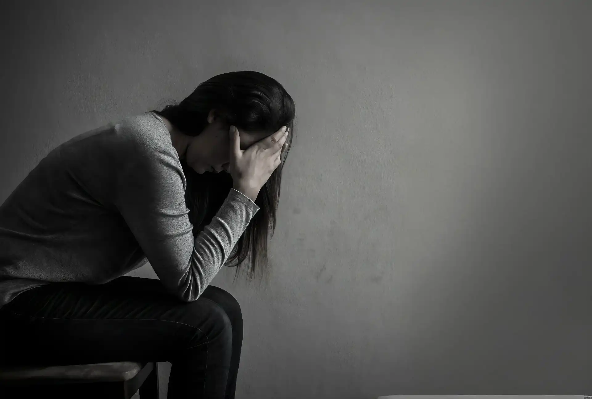 Woman sitting, expressing deep sadness.